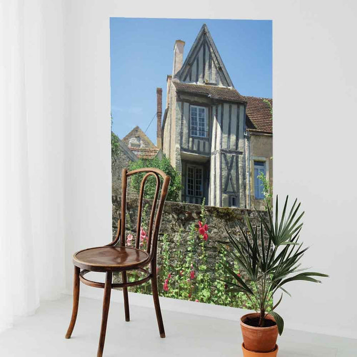 60 inch decal of a half timbered house with a wall and flowers in foreground installed on a wall with a chair and potted plant in foreground