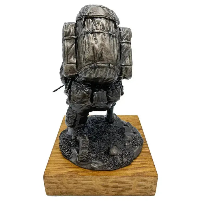 Rear view of Bronze Resin Kneeling Combat Statue with Helmet, highlighting detailed Bergen backpack and textured terrain on oak wooden base.  from  John Bull Clothing