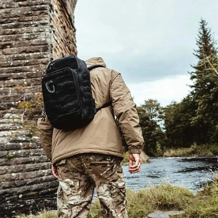 Person wearing Highlander Harrier 25L Clamshell Rucksack in black while trekking outdoors, highlighting its rugged and adventure-ready design.  from  John Bull Clothing