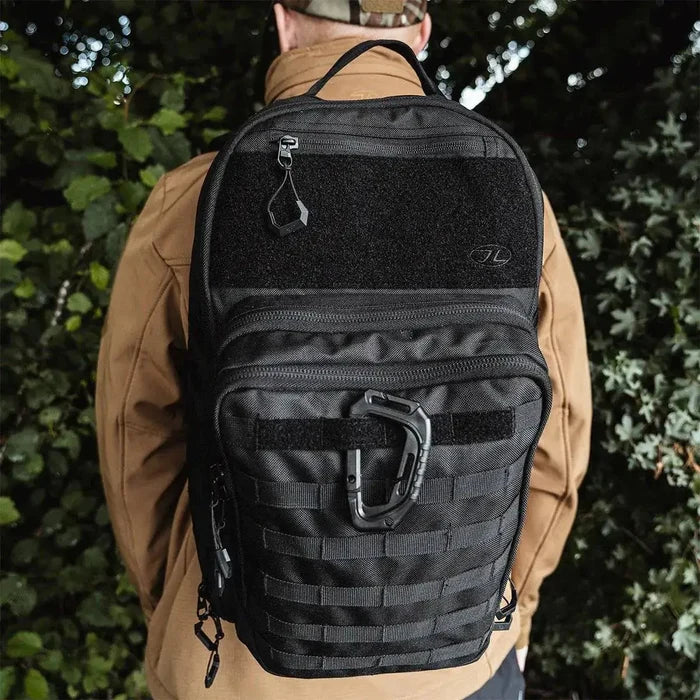 Close-up of Highlander Harrier 25L Clamshell Rucksack in black worn by a person, showcasing MOLLE webbing and tactical utility for versatile use.  from  John Bull Clothing