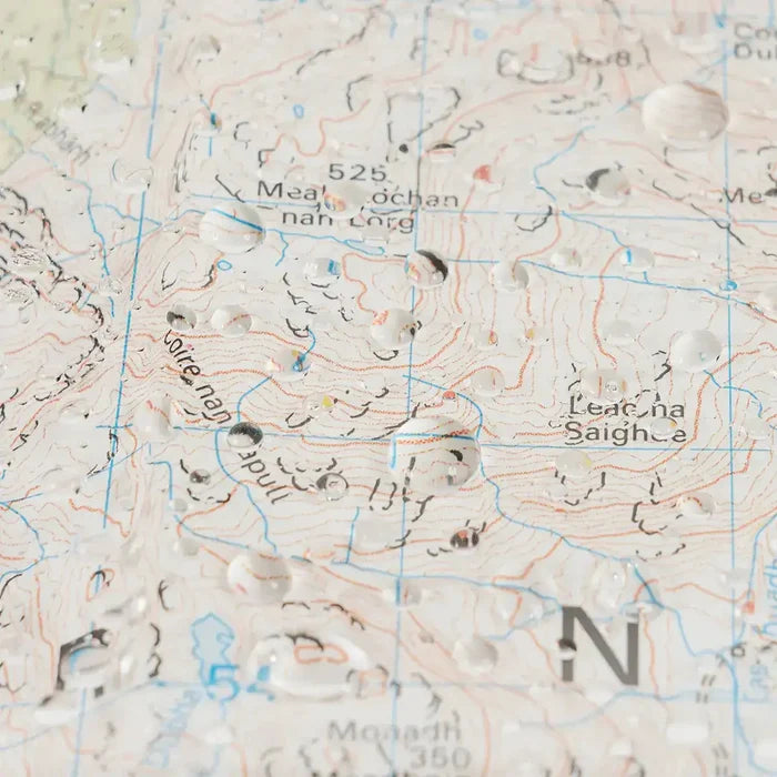 Close-up of topographic map inside Highlander Wanderer map case with water droplets, showing detailed terrain and contour lines for hillwalking