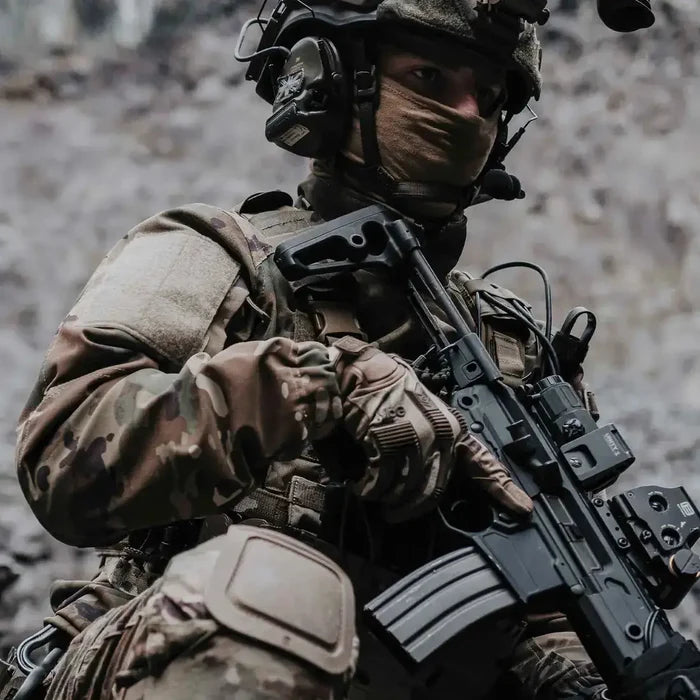Operator wearing MoG Target High Abrasion Ergoshield Gloves in Multicam while holding a rifle, showcasing tactical performance in combat-ready environments.  from  John Bull Clothing