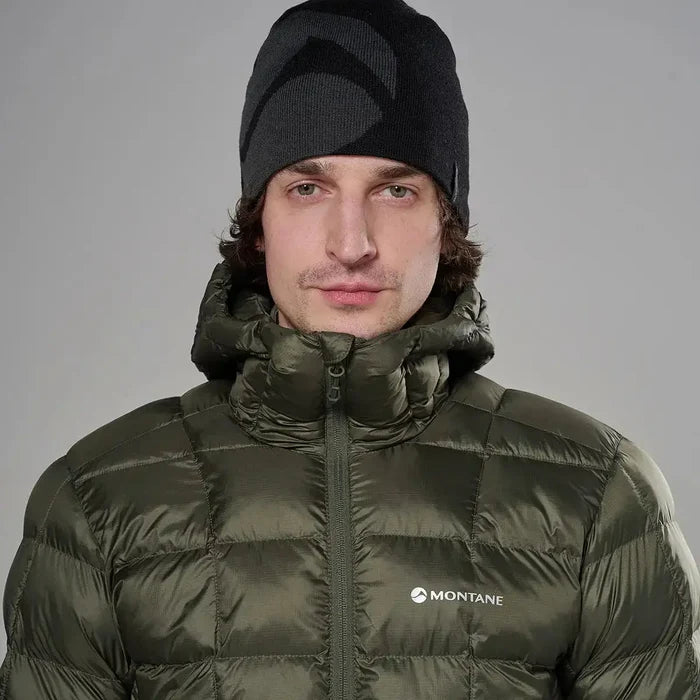 Male model wearing olive green Montane insulated puffer jacket with high collar and front zipper, paired with black beanie, on gray background