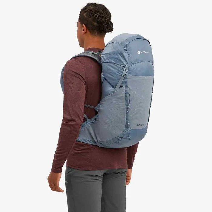 Rear view of a model wearing the Montane Trailblazer 32 Litre Backpack in blue, showing its contoured back panel and lightweight design for hiking.  from  John Bull Clothing