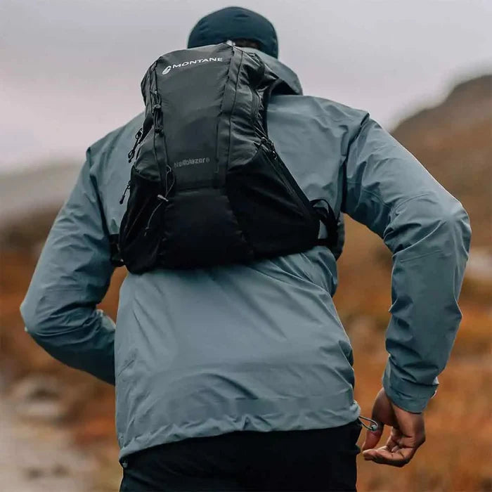 Runner wearing the Montane Trailblazer 8L Recycled Backpack in black, showcasing its snug fit and lightweight design for high-performance outdoor activities.  from  John Bull Clothing