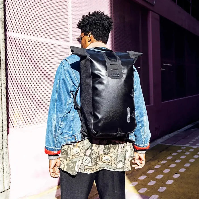 Model wearing Ortlieb Velocity 23L Dry Backpack in black, showcasing its urban style and functional design for everyday adventures.  from  John Bull Clothing