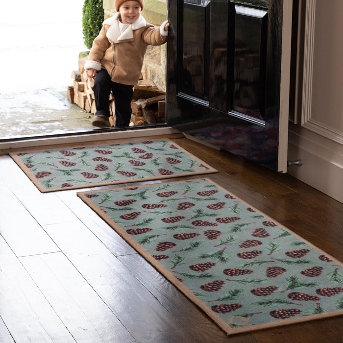 Pinecones Washable runner- 100% recycled cotton runner featuring scattered brown pinecones and green fern leaves.