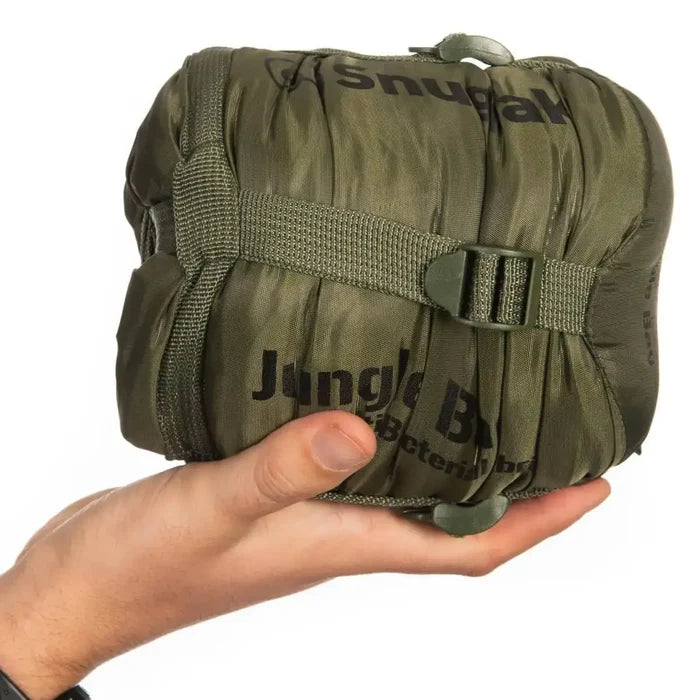 Olive green Snugpak Jungle Sleeping Bag with Mosquito Net packed into a compact bundle, shown in hand for size comparison.  from  John Bull Clothing
