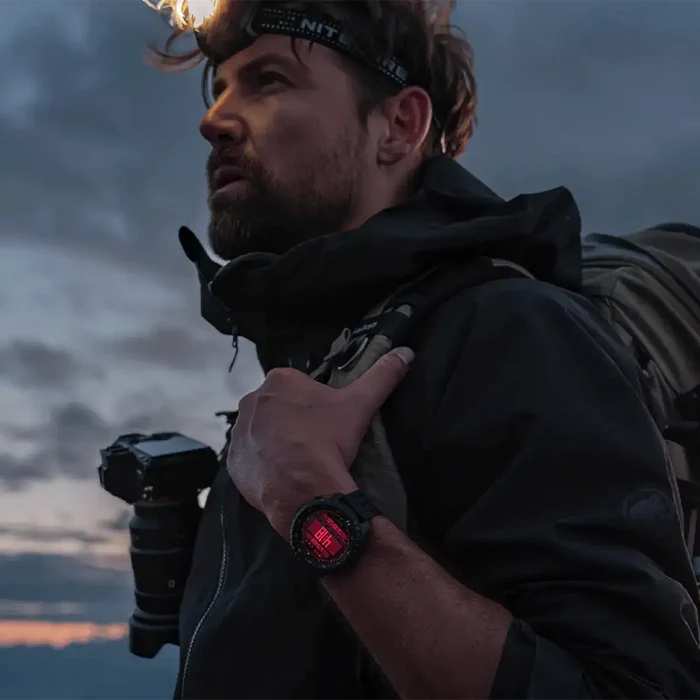 Male hiker wearing black Suunto Core 2 outdoor tactical GPS watch with digital display, rugged strap, and backpack in outdoor setting