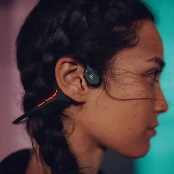 A person wearing Suunto Wing Open Ear Bluetooth Headphones, showing the secure fit and LED safety lights for outdoor activities.  from  John Bull Clothing