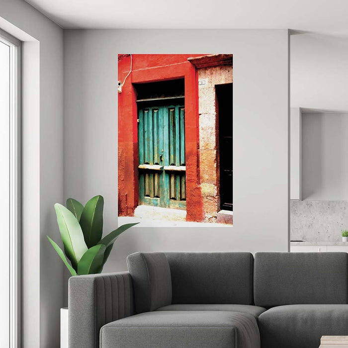 60 inch poster of a red framed green door of a Mexican home displayed on a wall above a sofa and plant