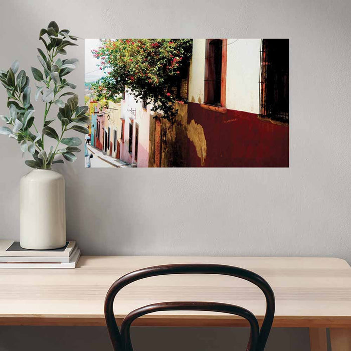 24 inch poster of Mexican homes along a street with red floral buses displayed above a desk and chair