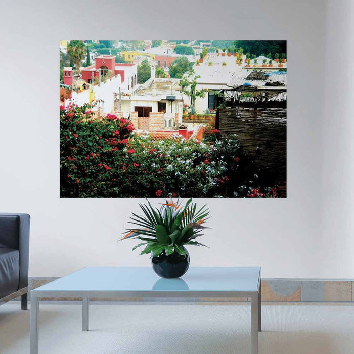 60 inch decal of a rooftop garden in Mexican town looking down on other homes installed on wall in a living room with coffee table in foreground