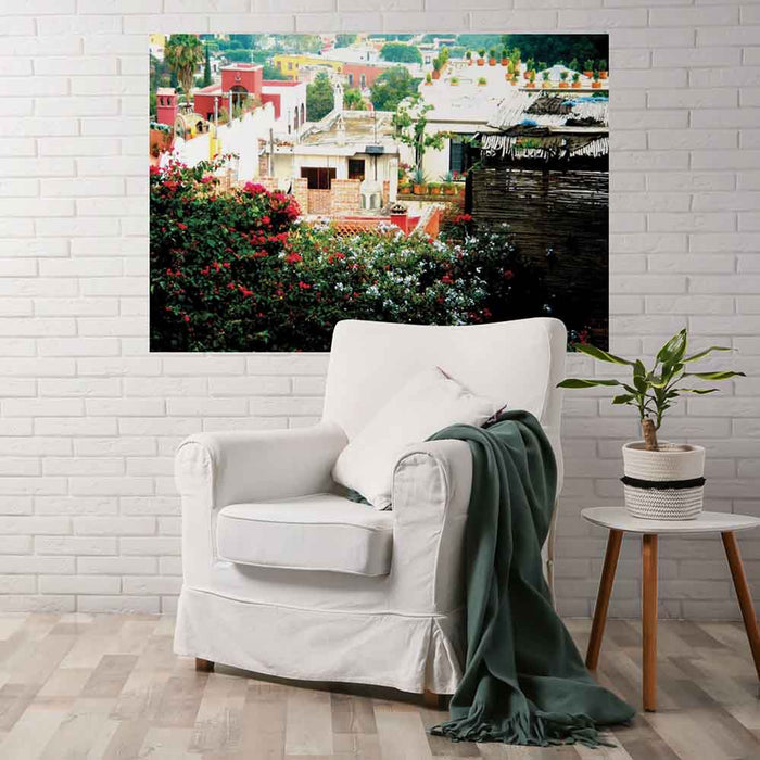 72 inch decal of a rooftop garden in Mexican town looking down on other homes installed on wall above a linen chair and table with potted plant