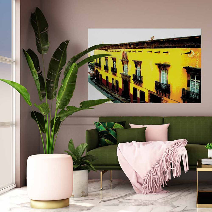 60 inch decal of yellow Mexican hotel with balconies installed on a wall above a sofa with pink blanket
