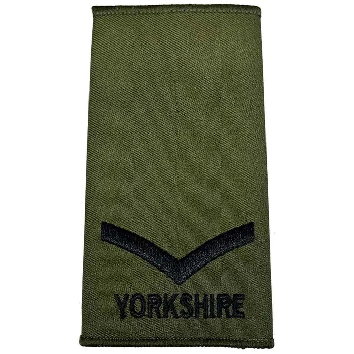 Yorkshire Regiment Olive Green Rank Slide featuring a single black chevron above 'YORKSHIRE' text, suitable for junior enlisted ranks. Lance Corporal from  John Bull Clothing